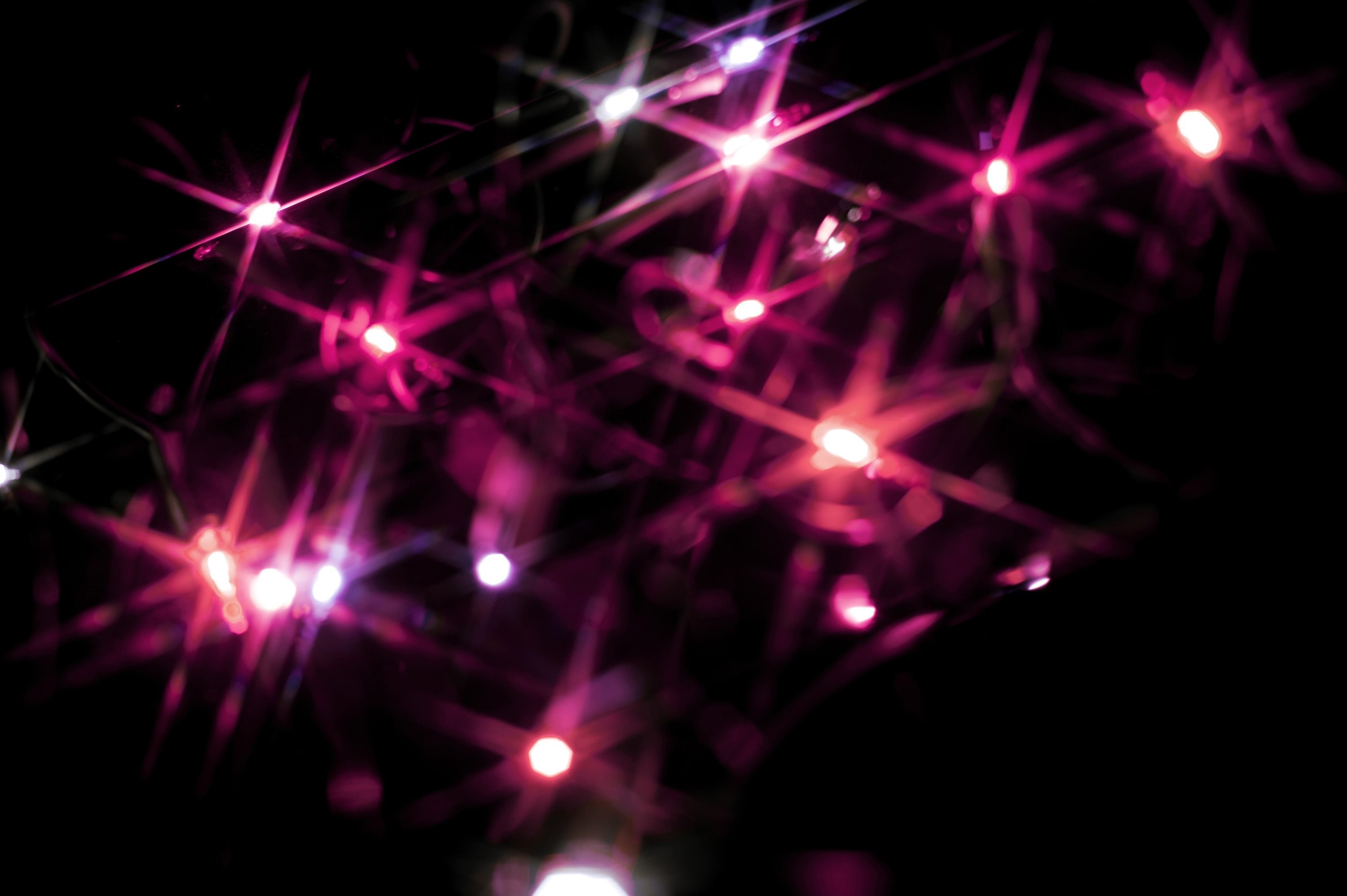 3000x1996 Christmas background of colourful vivid pink starburst lights scattered in  the darkness sparkling and glowing for