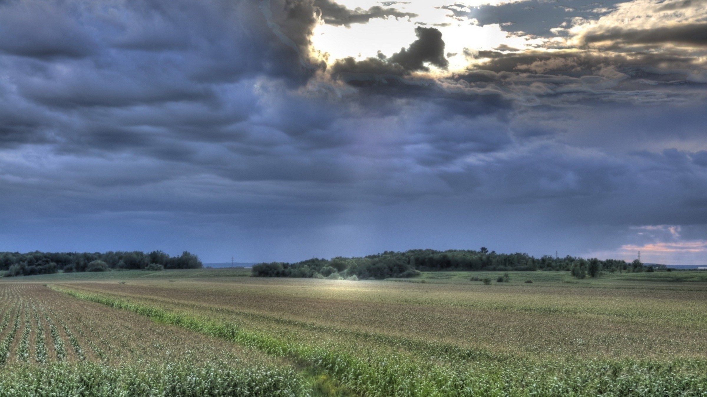 2400x1350 Sunrays through storm clouds over fields wallpaper