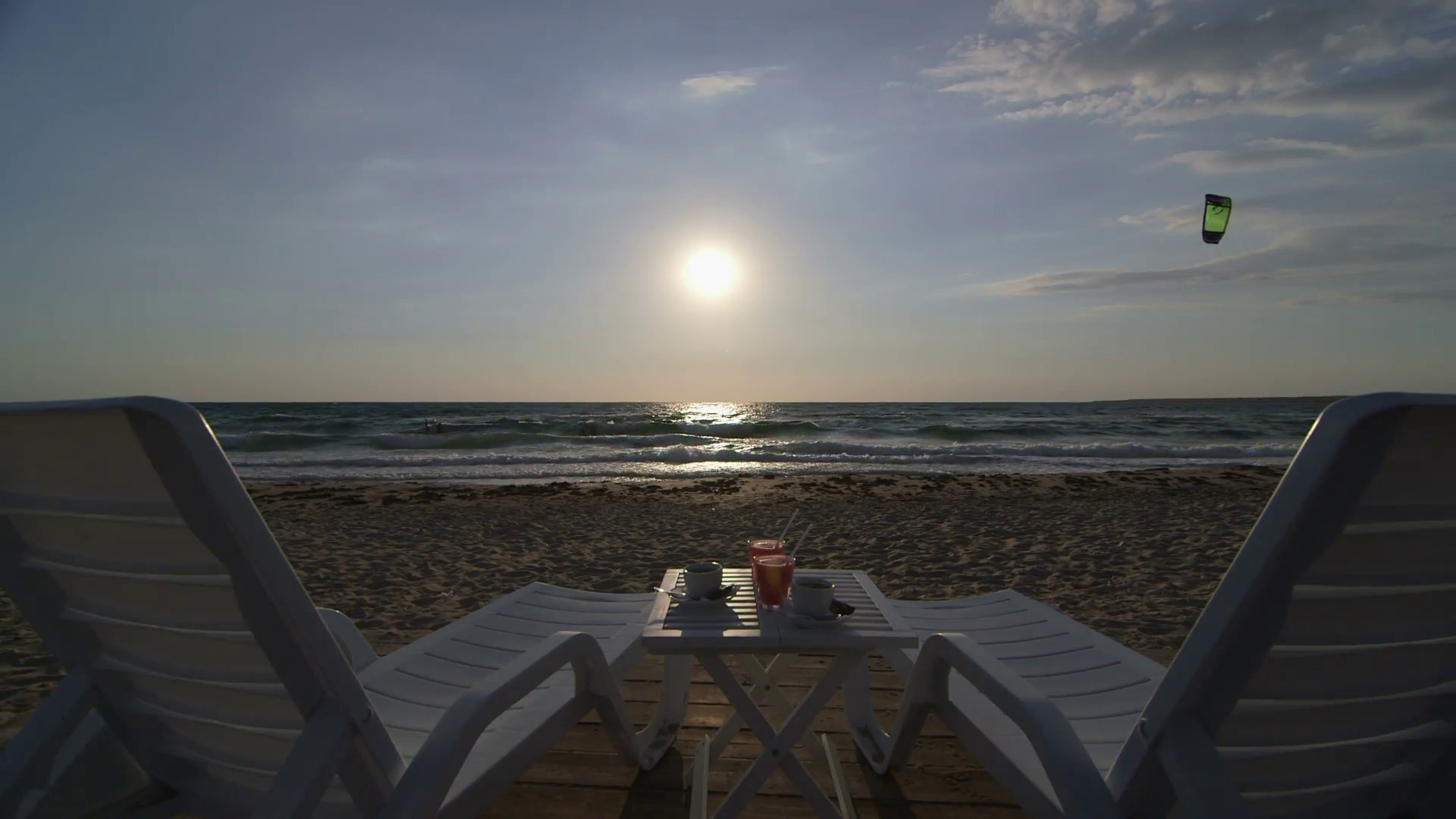 1920x1080 Two loungers, table with coffee and drinks on sandy summer beach at sunset.  Kitesurfer riding waves in the background Stock Video Footage - Storyblocks  ...