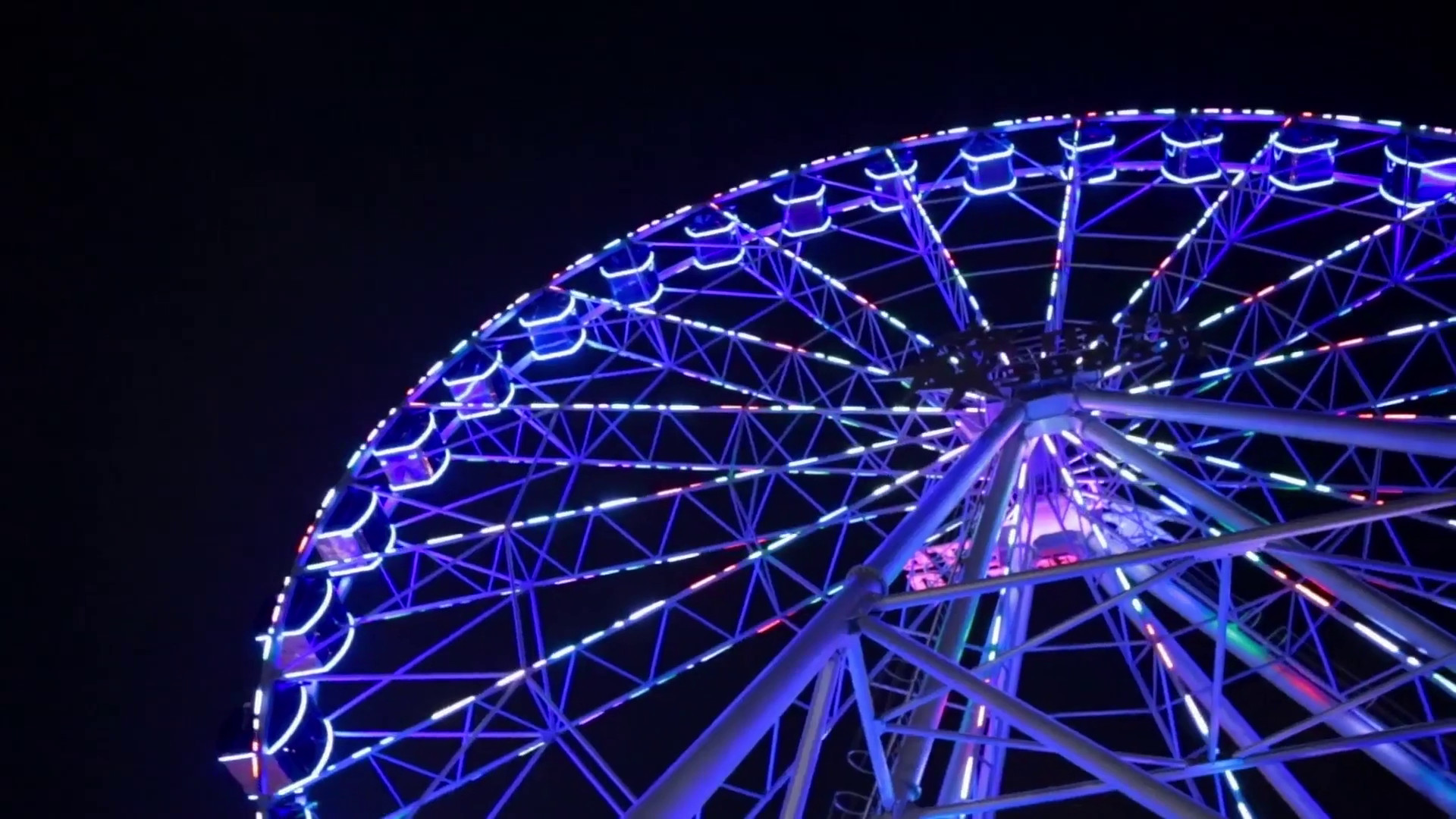 1920x1080 Ferris wheel in blue neon light on dark background, Part of Ferris wheel  with blue illumination against a black sky background at night.