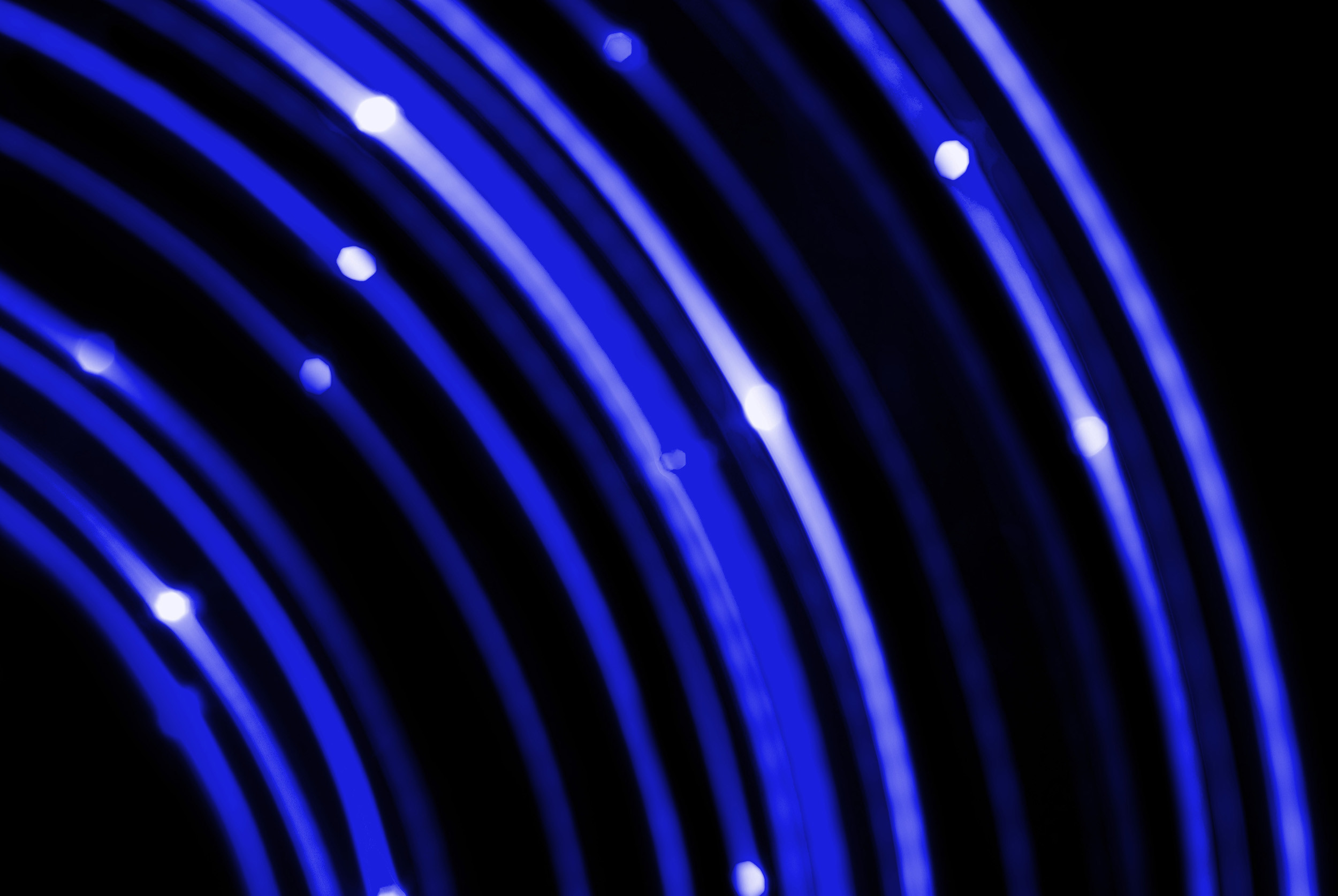 2500x1674 concentric curved blue coloured lines of light on a black background