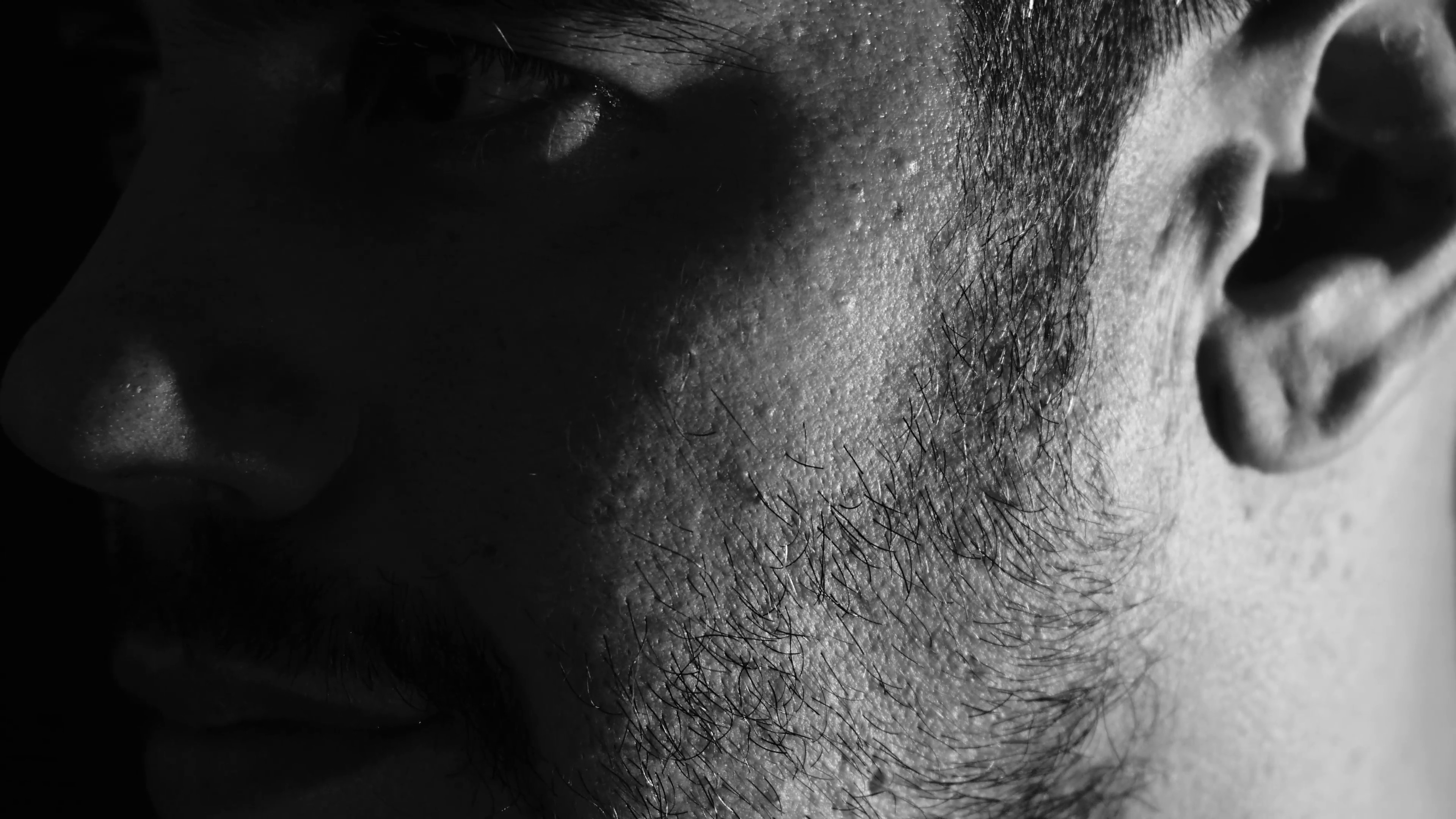 3840x2160 sad man looking into the camera: black background: depression, loneliness