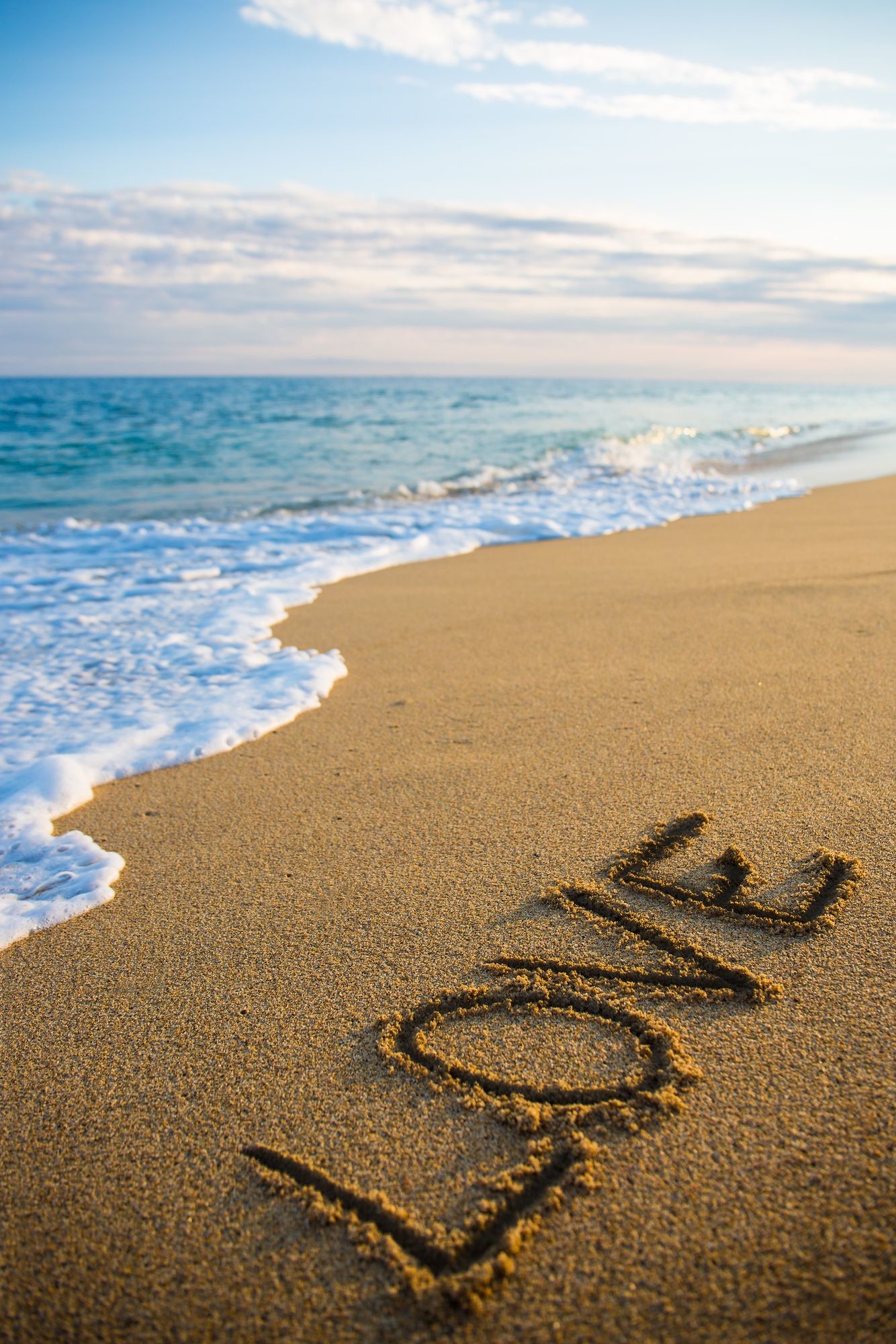 1334x2000 love concept - beach background with word love written in sand