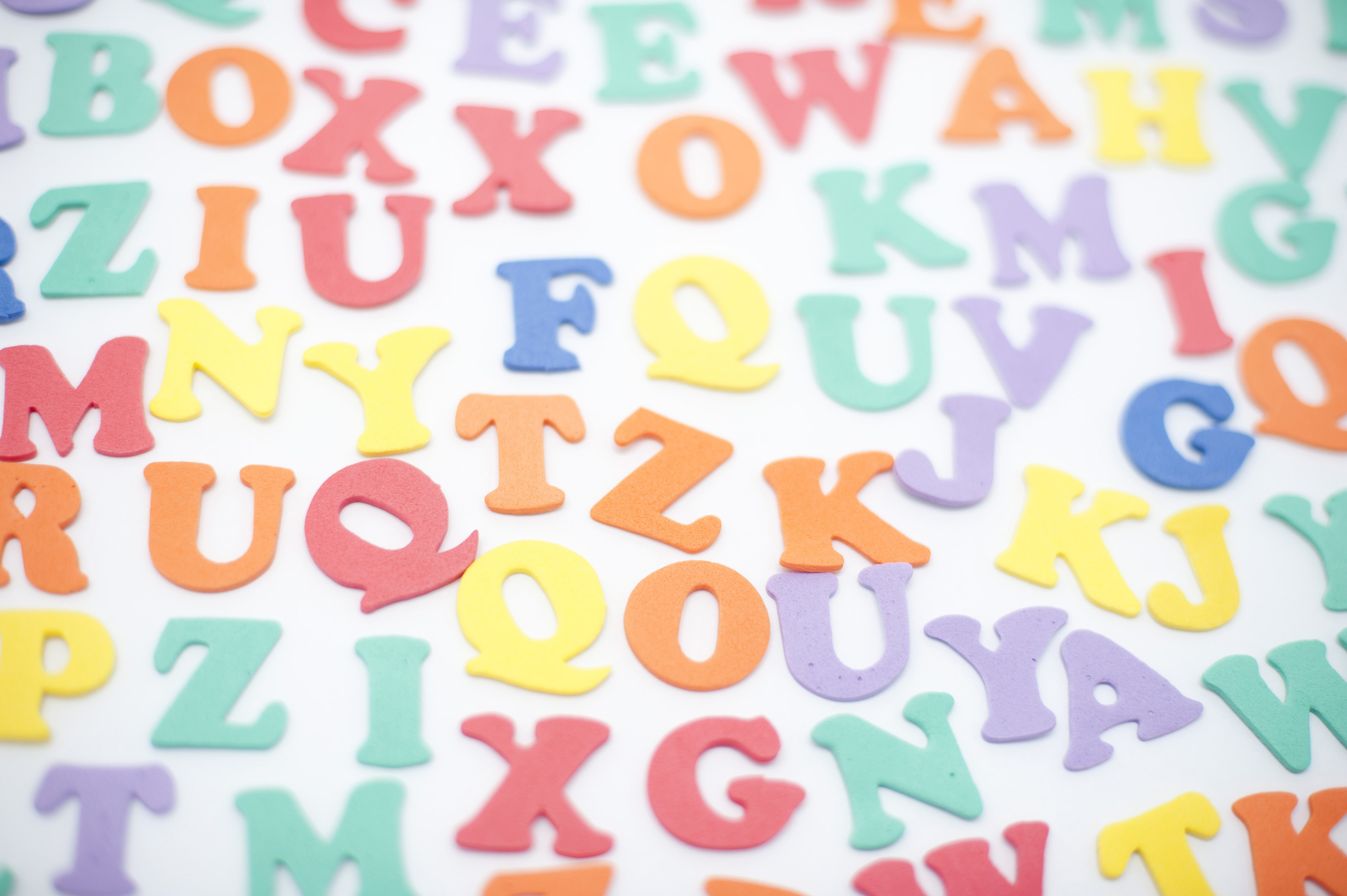 3200x2129 Colourful alphabet background with random scattered uppercase letters on a  white surface