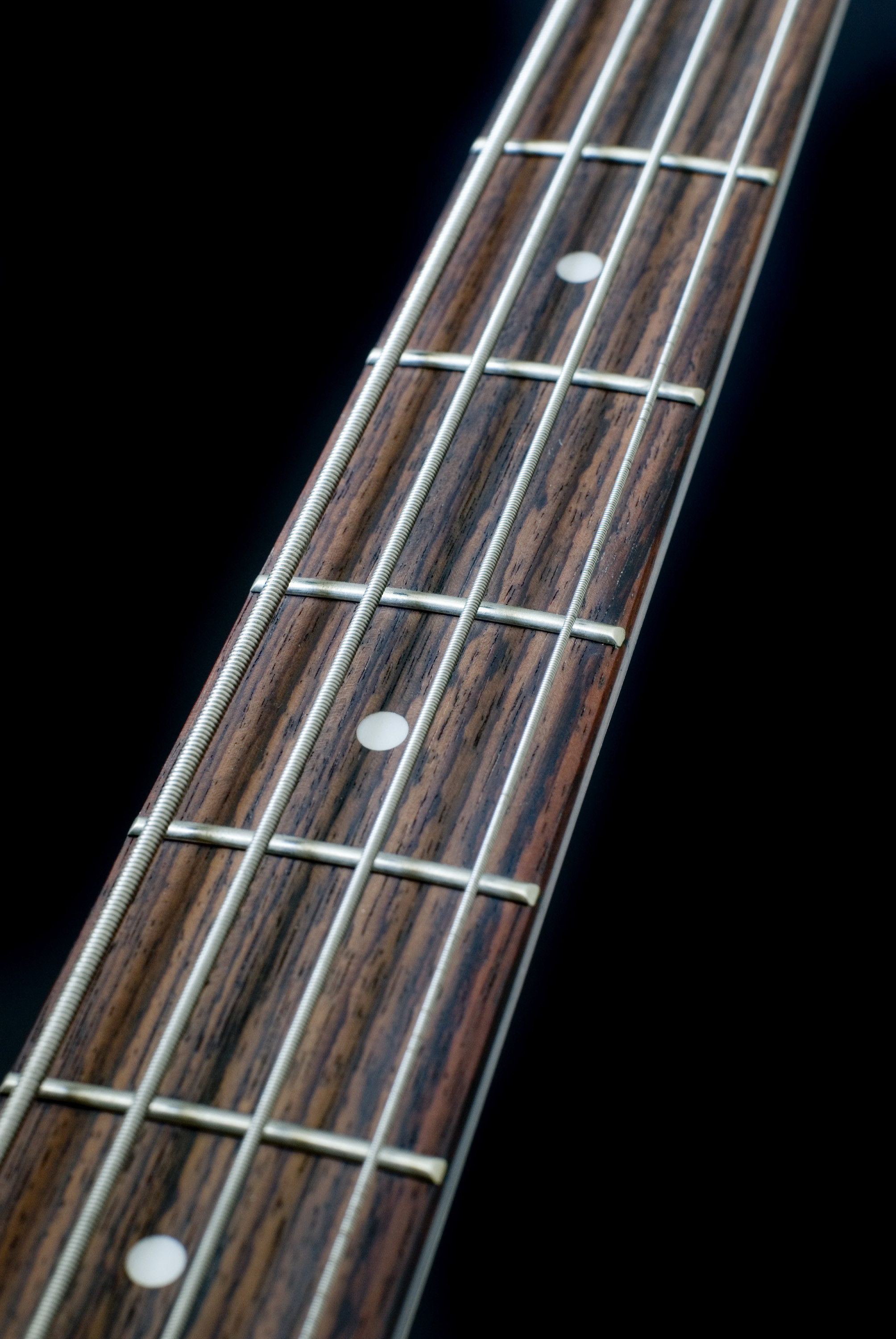 2008x3000 the neck of a bass guitar on a black backdrop