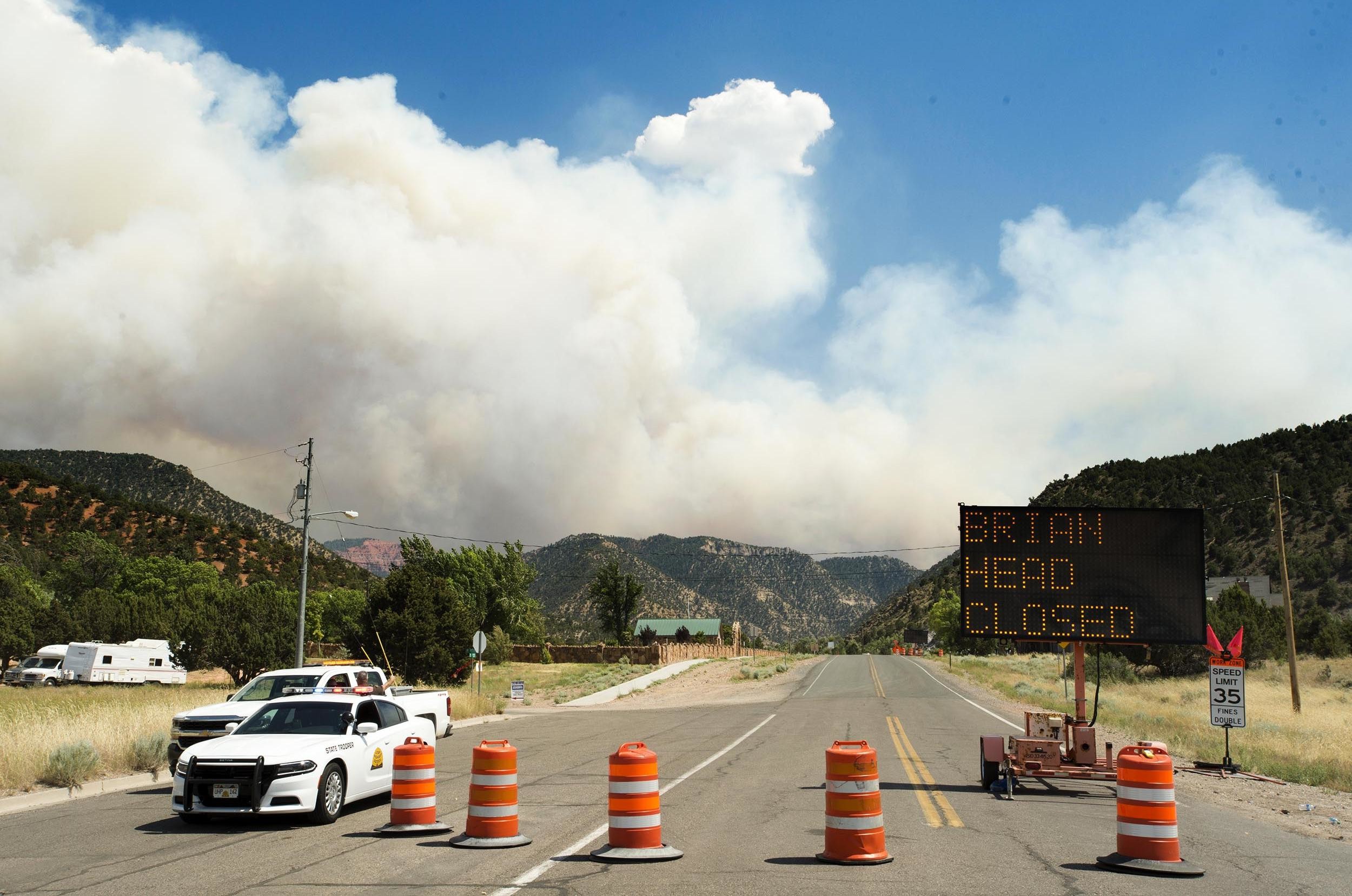 2500x1658 As smoke billow as a wildfire burns in the background, a roadblock closing  Highway 143