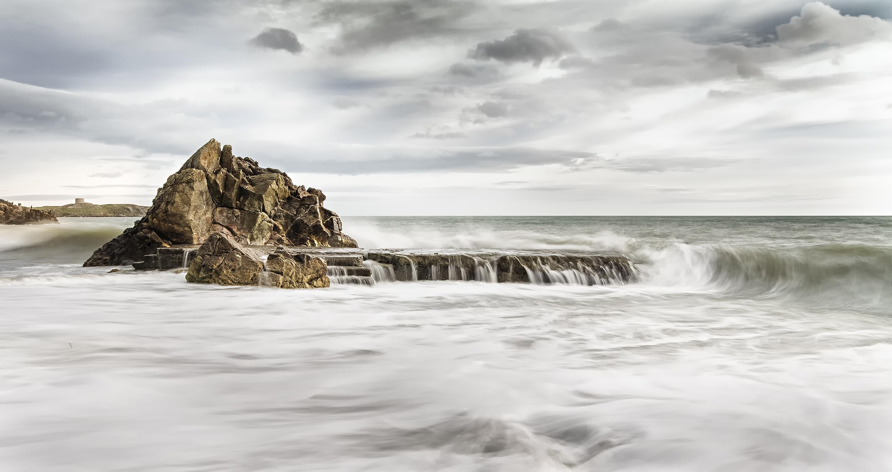 3000x1588 sea waves splashing on grey rock with grey cloudy sky preview