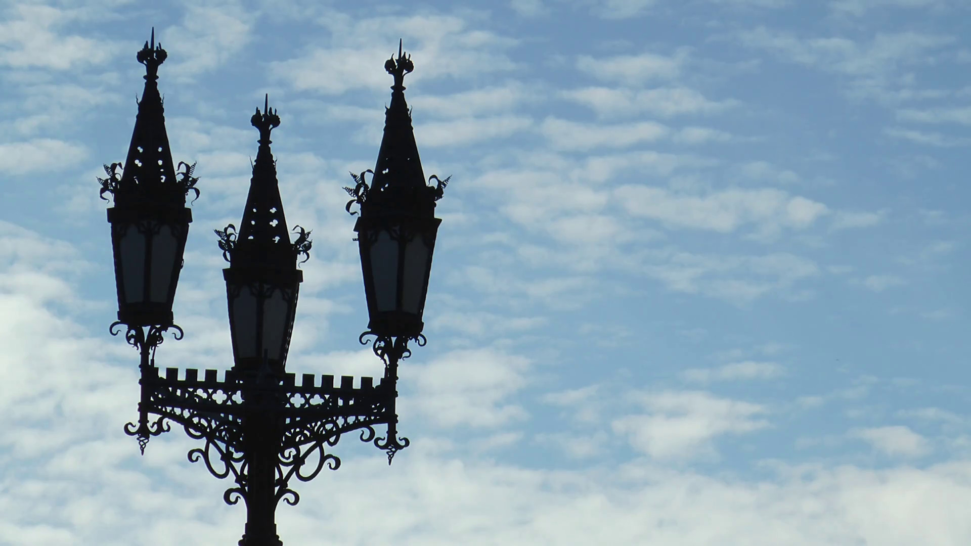 1920x1080 The dark silhouette of the pole with three Gothic street lamps on background  of blue cloudy sky in the late evening. Stock Video Footage - VideoBlocks
